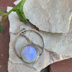 "Rainbow moonstone has always been one of my favorites, with its blue and purple flashes, and this stone is no exception, it's got a GORGEOUS flash. Moonstone is said to represent feminine power and hope, but is most commonly known to be the birthstone for those lucky enough to be born in June. A rainbow moonstone is set in a sterling and fine silver bezel. I cut the back of the bezel out because when the light hits it just right, she just glows. The stone sits on top of a circular base which has two jump rings that I left open so you can string it onto a necklace of your choosing. This one-of-a-kind pendant is approximately 1.5\" in diameter. Please note that this listing is for the pendant only; necklace is not included. This pendant is definitely a statement pendant, so I recommend pair Unique Iridescent Moonstone Jewelry, Minimalist Moonstone Jewelry For Healing, Minimalist Moonstone Moon-shaped Jewelry, Mystical Moonstone Jewelry With Large Stone, Moonstone Jewelry With Large Round Stone, Bohemian Moonstone Round Pendant Jewelry, Bohemian Moonstone Jewelry With Moon Phase Detail, Bohemian Moonstone Jewelry With Moon Phase, Minimalist Moonstone Moon Jewelry