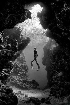 a person swimming in the water through a cave