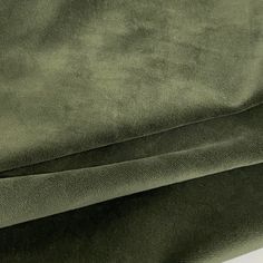 a close up view of the fabric on a green velvet bed coverlet with white piping