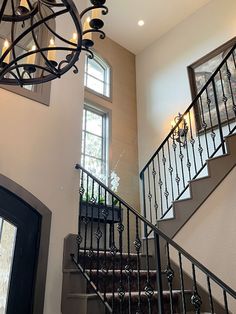 a staircase with wrought iron railing and chandelier