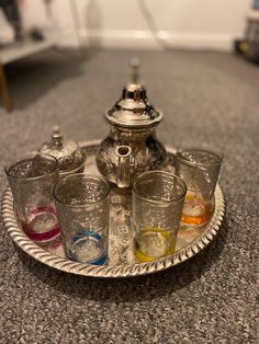 a silver tea pot sitting on top of a metal tray filled with cups and glasses