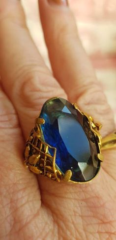 Beautiful vintage ring with intricate detailing to either side. The stone is a deep blue and the gold metal shows signs of once having some blackness. Vintage Brass Rings With Intricate Design, Antique Brass Rings With Intricate Design, Blue Brass Ring Jewelry, Antique Blue Brass Jewelry, Vintage Blue Filigree Rings, Victorian Bronze Brass Ring, Vintage Blue Sapphire Ring With Intricate Design, Antique Sapphire Gemstone Rings, Antique Blue Gemstone Rings