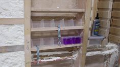 the shelves are filled with plastic containers and tools for painting or decorating in an unfinished room