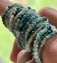 a close up of a person's hand holding some kind of beaded bracelet