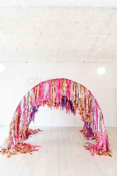 an arch made out of ribbons and streamers in a room with white flooring