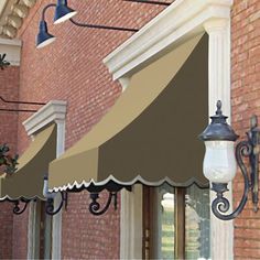 an awning on the side of a brick building with two lamps hanging from it