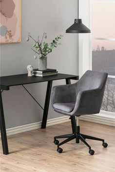 a desk with a chair, lamp and vase on it in front of a window