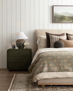 a bedroom with a bed, nightstand and painting on the wall above it's headboard