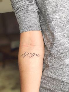 a woman's arm with a mountain tattoo on the left side of her arm