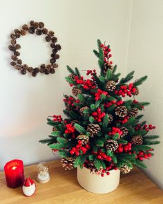 a small christmas tree sitting on top of a wooden table next to a red candle