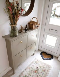 a vase filled with flowers sitting on top of a wooden dresser next to a door