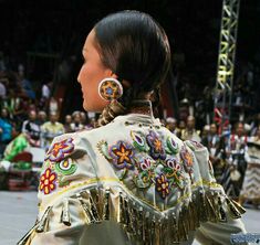 a woman in an elaborately decorated outfit is looking at something while people watch from the stands