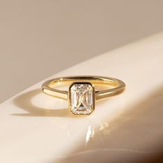 a gold ring with an emerald cut diamond