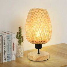 a wooden table with a lamp on top of it next to books and cacti