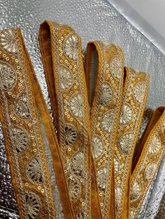 several pieces of gold and silver cloth with intricate designs on them, sitting in a pile