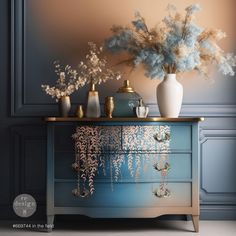 vases and flowers sit on top of a blue dresser in a room with gold trim