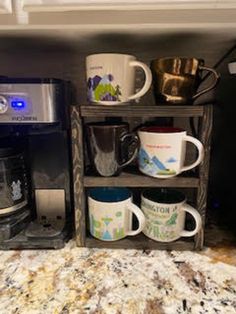 there are many coffee mugs on the shelf next to the coffee maker and toaster