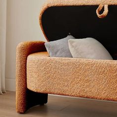 an upholstered bench with two pillows on it's back and the seat open