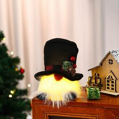 a christmas scene with a small house and a top hat on a table next to a tree