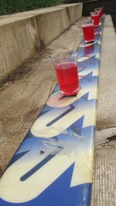 three shot glasses sitting on top of a blue and white skateboard