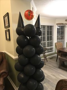 black balloons are stacked on top of each other in front of a dining room table