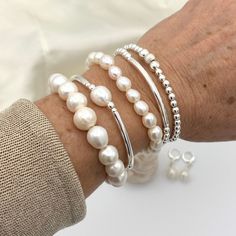 a woman's arm with three bracelets on it and two pearls attached to the wrist