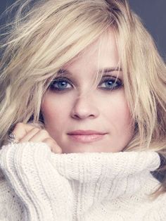 a woman with blonde hair and blue eyes wearing a white turtle neck sweater looking at the camera