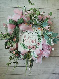 a wreath with pink flowers and greenery on it that says, home is where your mom is