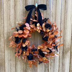 an orange and black wreath hanging on the side of a wooden fence