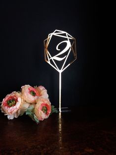 a bouquet of flowers sitting on top of a wooden table next to a light that is shaped like a diamond