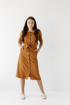 Introducing the 'Bronwyn' Tencel dress! This flattering dress features a button front detail and is finished off with a beautiful belt that ties together an entire look. Pair with low heels for an elevated and sophisticated office look! Exclusively designed by us with you in mind. 75% Tencel 25% Linen Hand Wash Cold Do Not Bleach Hang to Dry Low Iron if Needed Do Not Dry Clean Unlined Functional, nursing friendly buttons! Model Height 5'7" | Wearing Size Small Please carefully measure a similar Formal Button-up Midi Dress With Tie Waist, Modest Button-up Dresses For Workwear, Brown Midi Dress With Button Closure For Work, Brown Midi Dress With Button Closure, Casual Knee-length Belted Dress For Work, Casual Workwear Dresses With Belted Cuffs, Brown Buttoned Midi Dress, Belted Knee-length Dress For Work, Fall Midi Dress With Button Closure For Work