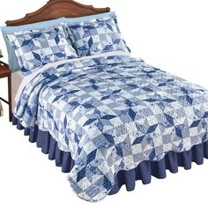 a bed with blue and white quilts on it