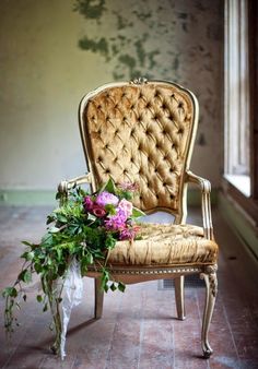 a chair with flowers in it sitting on the floor next to a plant and window