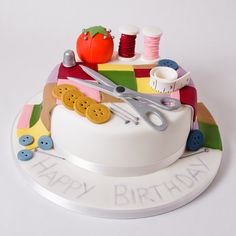 a birthday cake decorated with buttons and sewing supplies