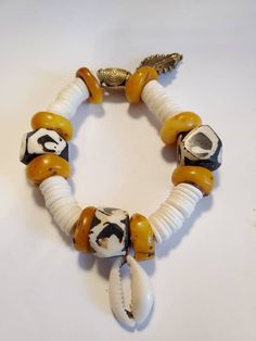 African Batik Bone White Hesihi Natural Amber Beeswax Bead Stretch Bracelet. Batik Bone has geometric design with eyes. Beads are large and comfortable. White round flat Hesihi beads in the design. Brown Amber Beeswax Beads.  Blends well with the black and white beads. Cowrie Shell attached. Measures 7" to 7.5" wrist African Beaded Bracelets, Ocean Springs Ms, Beaded Memory Wire Bracelets, Ocean Springs, Beaded Memory Wire, Statement Choker Necklace, Natural Amber, African Beads, African Jewelry