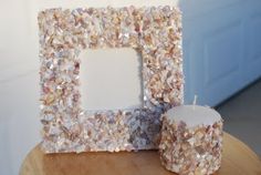 a wooden table topped with a white frame and two small candles on top of it