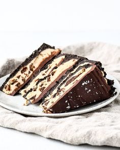 a slice of chocolate cake on a plate with a white towel and napkin in the background