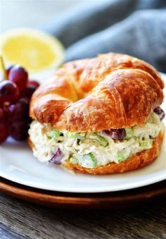 a croissant sandwich on a plate with grapes