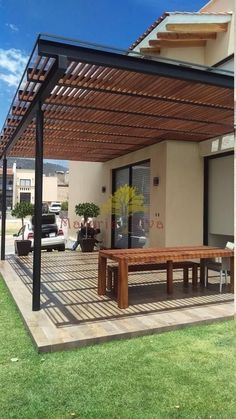 an outdoor patio with a wooden table and bench under a pergolated covering over it