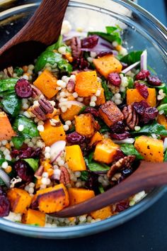 a salad with carrots, spinach, corn and cranberries in it