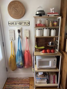 there are three bags hanging on the wall next to each other in front of a microwave