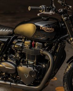 a black and gold triumph motorcycle parked in front of a building with polka dots on the floor