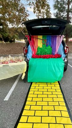 the trunk of a car is decorated with colorful streamers and tissue paper as it sits in a parking lot