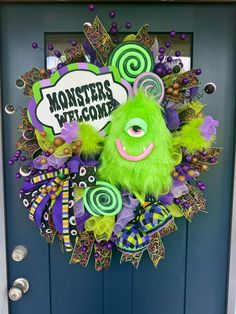 a green monster wreath on a blue door with the words monsters welcome written above it