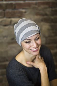 a smiling woman wearing a gray and white striped headband with her hand on her chin