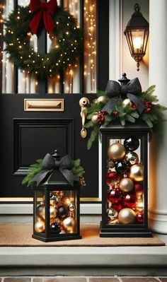 two lanterns with christmas decorations on them sitting in front of a door decorated for the holiday season