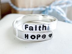 "The \"Faith, Hope, Love\" Wrap Ring is a beautiful and meaningful piece of jewelry that is sure to bring serenity and inspiration to your daily life.  Featuring the words \"Faith, Hope, Love\" hand-stamped on a wrap ring in your choice of precious metal, this ring is a powerful reminder of the values that are most important to you. Wear it on your middle finger, thumb, or pinky, or adjust the size to fit any other finger. The fully customizable size also makes it an excellent gift for someone special. The \"Faith, Hope, Love\" Wrap Ring is more than just a piece of jewelry - it's a daily reminder to stay true to your beliefs and to find strength and inspiration in the things that matter most. So if you're looking for a meaningful and uplifting accessory, look no further than the \"Faith, Inspirational Adjustable Ring, Engraved Ring, Wrap Ring, Midi Rings, Faith Hope Love, Hope Love, Wrap Rings, Be True To Yourself, Precious Metal