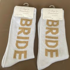 two white socks with gold glitter bride and groom's name on the bottom, one is