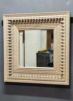 a mirror is hanging on the wall in front of a gray wall with a white frame