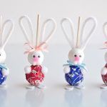 four little bunny figurines are lined up in the shape of eggs and carrots